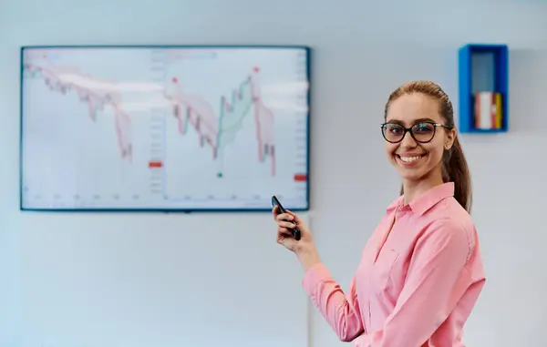 stock image On Stage, Successful Female Speaker Presents Technological Product, Uses Remote Control for Presentation, Showing Infographics, Statistics Animation on Screen. Live Event Device Release. 