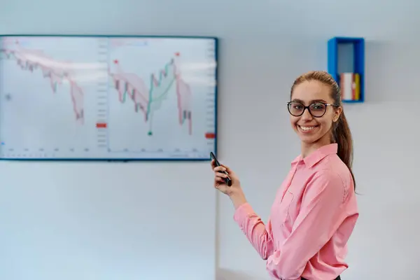 Stock image On Stage, Successful Female Speaker Presents Technological Product, Uses Remote Control for Presentation, Showing Infographics, Statistics Animation on Screen. Live Event Device Release. 