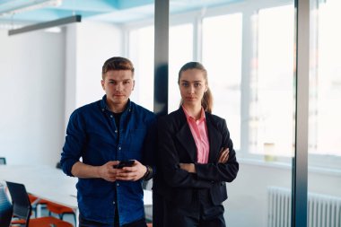 Bir bilişim şirketinin müdürü, meslektaşıyla birlikte modern bir ofis ortamında poz veriyor.. 