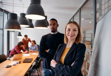 Sarışın bir yönetmen ve genç bir Afrikalı Amerikalı girişimci bir ofiste yan yana dururken, takımları yaklaşan toplantı için arka planda hazırlanıyor.. 