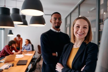 Sarışın bir yönetmen ve genç bir Afrikalı Amerikalı girişimci bir ofiste yan yana dururken, takımları yaklaşan toplantı için arka planda hazırlanıyor.. 