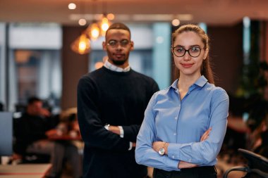 Çağdaş bir ofis ortamında, sarışın bir iş kadını ve onun Afrikalı Amerikalı iş ortağı, internetteki belgelere odaklanmış bir kararlılıkla bakıyorlar.