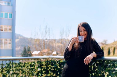 Bir iş kadınının, sakin terasında kahve molasının tadını çıkarırken, bir an için sakinliğini hissedin. Şehir koşuşturmasının ortasında gençleşir.