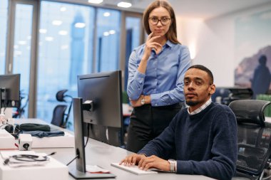 Çağdaş bir ofis ortamında, sarışın bir iş kadını ve onun Afrikalı Amerikalı iş ortağı, internetteki belgelere odaklanmış bir kararlılıkla bakıyorlar.