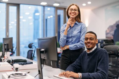 Çağdaş bir ofis ortamında, sarışın bir iş kadını ve onun Afrikalı Amerikalı iş ortağı, internetteki belgelere odaklanmış bir kararlılıkla bakıyorlar.