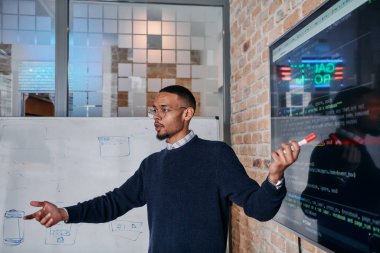 Afrikalı Amerikalı iş adamı iş stratejisini meslektaşlarına sunuyor, işbirliğini ve ileriyi düşünmeyi teşvik ediyor..