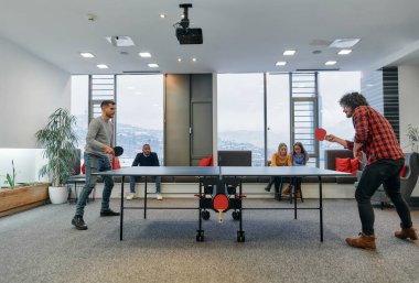  İş arkadaşları masa tenisi oynamak, iş yerinde takım çalışması ve arkadaşlığı teşvik etmek için işe ara veriyorlar.. 