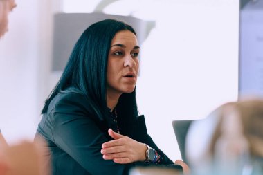 Liderlik ve işbirliğinin özünü yakalayan bu vesikalık portre, profesyonel bir iş kadınının meslektaşlarıyla verimli bir toplantıya özenle rehberlik ettiğini gösteriyor.