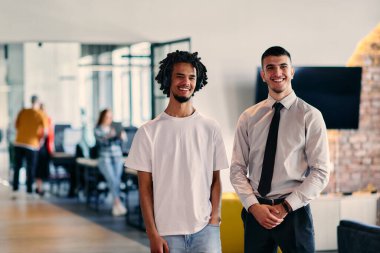 Aralarında Afro-Amerikalı bir işadamı ve gömlek ve kravat takmış genç bir liderin de bulunduğu bir grup meslektaşı, dinamik bir karışımı temsil eden modern bir çalışma merkezi ofisinde birlikte poz veriyorlar.