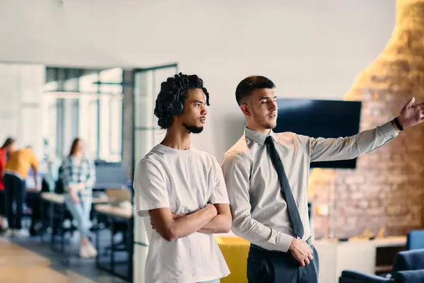 stock image A group of colleagues, including an African American businessman and a young leader in a shirt and tie, pose together in a modern coworking center office, representing a dynamic blend of