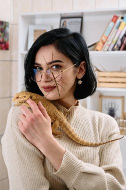 A young woman poses with her two pets, a bearded dragon and a stick insect, in this heartwarming photo. clipart