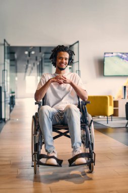 Tekerlekli sandalyedeki Afro-Amerikalı genç girişimci, iş arkadaşları tarafından modern ofis ortamında, iş yerinde çeşitlilik ve işbirliğinin somutlaştırılması ile çevrilidir.. 