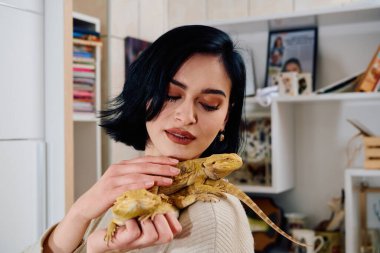Neşeli bir anda güzel bir kadın, iki sevimli sakallı ejderha evcil hayvanıyla poz veriyor, sevgi ve arkadaşlık yayıyor..