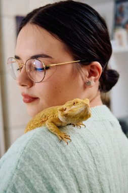 Neşeli bir anda güzel bir kadın, sevimli sakallı ejderha evcil hayvanlarıyla poz veriyor, sevgi ve arkadaşlık yayıyor..
