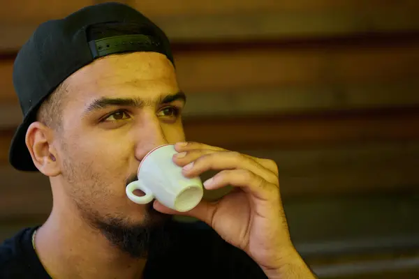 stock image A close up capture of a Middle Eastern teenager indulging in a moment of coffee enjoyment, reflecting on relaxation and cultural affinity. 