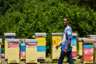  Geleneksel Sudan kıyafetleri içinde giyinmiş Afrikalı Amerikalı gençler doğanın güzelliği içinde küçük arı yetiştiriciliği işlerini araştırıyor.