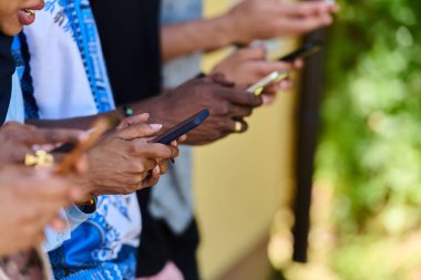 Çeşitli gençlerden oluşan bir grup, akıllı telefonlarına dalmış, modern bağlantılarını ve sosyal etkileşimlerini sergiliyorlar..