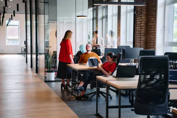 Stock image A diverse group of business professionals collaborates in a modern startup coworking center, utilizing a mix of paper-based and technological tools such as mobile phones and computers to collectively