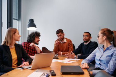 Girişimcilerden oluşan çeşitli bir iş ekibi, modern ofis ortamında önemli bir toplantı düzenliyor ve projeler geliştiriyor..