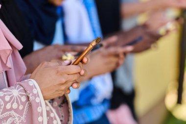 Çeşitli gençlerden oluşan bir grup, akıllı telefonlarına dalmış, modern bağlantılarını ve sosyal etkileşimlerini sergiliyorlar..