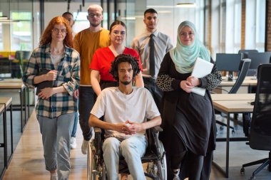 Genç iş adamlarından oluşan çeşitli bir grup, modern bir girişim olan cam kaplı bir ofiste, tekerlekli sandalyedeki bir kişi, bir Afrikalı Amerikalı genç adam ve bir tesettür ile bir araya geliyor.