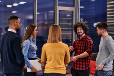 Çeşitli iş adamları bir ofis ortamında kahve molası sırasında şirket projeleri hakkında canlı bir tartışmaya giriştiler.
