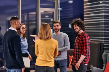 Çeşitli iş adamları bir ofis ortamında kahve molası sırasında şirket projeleri hakkında canlı bir tartışmaya giriştiler.