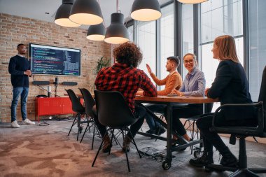 Kurumsal bir ortamda, Afrikalı-Amerikalı bir işadamı bir toplantıya liderlik eder, özenli ekibine tutkuyla bir iş planı sunar, işbirliği ve stratejik düşünmeyi teşvik eder.. 