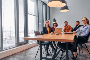 Girişimcilerden oluşan çeşitli bir iş ekibi, modern ofis ortamında önemli bir toplantı düzenliyor ve projeler geliştiriyor..