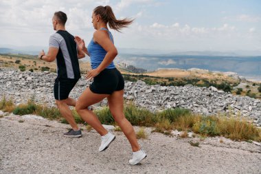  Couple conquer challenging mountain trails during an invigorating morning run. clipart