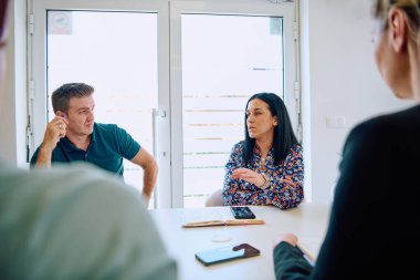 Çeşitli iş adamları modern cam duvarlı bir ofisteki projeler hakkında tartışmaya giriştiler.. 