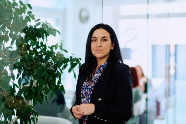 Çapraz kollu bir iş kadını, ofis ortamında kendine güven ve otorite yayıyor..