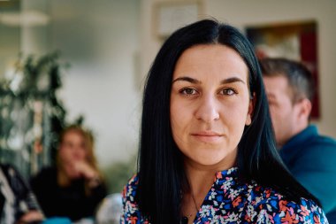 Liderlik ve işbirliğinin özünü yakalayan bu vesikalık portre, profesyonel bir iş kadınının meslektaşlarıyla verimli bir toplantıya özenle rehberlik ettiğini gösteriyor.