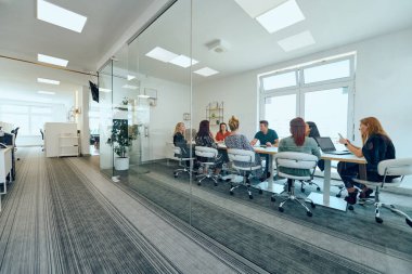 Çeşitli iş adamları modern cam duvarlı bir ofisteki projeler hakkında tartışmaya giriştiler.. 