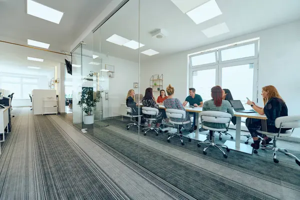 Çeşitli iş adamları modern cam duvarlı bir ofisteki projeler hakkında tartışmaya giriştiler.. 