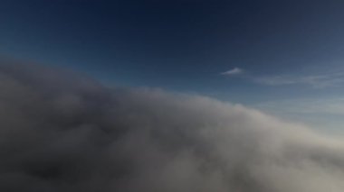 Dağlarda taze bir sabahta inanılmaz güzel bir bulutun içinden uçmak. Beyaz tüylü bulutlardan oluşan FPV insansız hava aracı açık mavi gökyüzünde usulca hareket ediyor