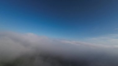 Taze bir yaz sabahı dağlarda muhteşem bir bulutlar arasında uçmak. Beyaz tüylü bulutlardan oluşan FPV insansız hava aracı açık mavi gökyüzünde usulca hareket ediyor