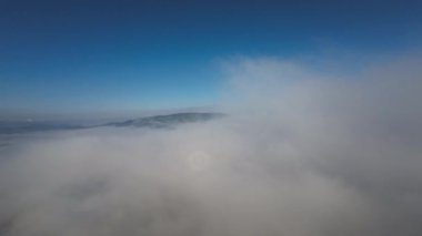 Taze bir yaz sabahı dağlarda muhteşem bir bulutlar arasında uçmak. Beyaz tüylü bulutlardan oluşan FPV insansız hava aracı açık mavi gökyüzünde usulca hareket ediyor