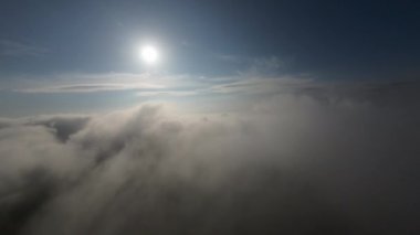 Dağlarda taze bir sabahta inanılmaz güzel bir bulutun içinden uçmak. Beyaz tüylü bulutlardan oluşan FPV insansız hava aracı açık mavi gökyüzünde usulca hareket ediyor