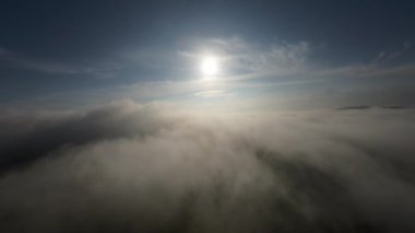 Taze bir yaz sabahı dağlarda muhteşem bir bulutlar arasında uçmak. Beyaz tüylü bulutlardan oluşan FPV insansız hava aracı açık mavi gökyüzünde usulca hareket ediyor