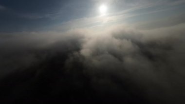 Dağlarda taze bir sabahta inanılmaz güzel bir bulutun içinden uçmak. Beyaz tüylü bulutlardan oluşan FPV insansız hava aracı açık mavi gökyüzünde usulca hareket ediyor