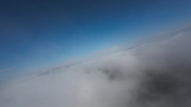 Taze bir yaz sabahı dağlarda muhteşem bir bulutlar arasında uçmak. Beyaz tüylü bulutlardan oluşan FPV insansız hava aracı açık mavi gökyüzünde usulca hareket ediyor