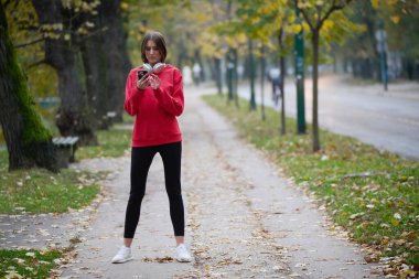 Atletik genç kadın, koşudan ve esnemeden sonra nefes alıyor ve dinleniyor. Sokakta Kadın Eğitimi ve Egzersizleri. Zayıf ve formda bir kız aktif fitness eğitiminden sonra esniyor.. 