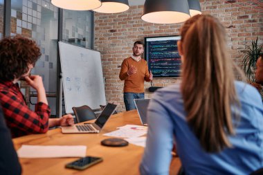 Kurumsal bir kurum kuran bir işadamı, bir toplantı düzenler, özenli ekibine tutkuyla bir iş planı sunar, işbirliği ve stratejik düşünmeyi teşvik eder.. 