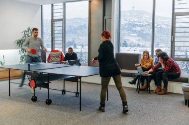  İş arkadaşları masa tenisi oynamak, iş yerinde takım çalışması ve arkadaşlığı teşvik etmek için işe ara veriyorlar.. 