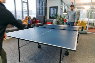  İş arkadaşları masa tenisi oynamak, iş yerinde takım çalışması ve arkadaşlığı teşvik etmek için işe ara veriyorlar.. 