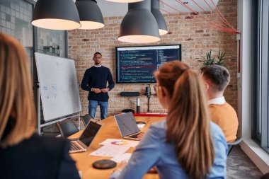 Kurumsal bir ortamda, Afrikalı-Amerikalı bir işadamı bir toplantıya liderlik eder, özenli ekibine tutkuyla bir iş planı sunar, işbirliği ve stratejik düşünmeyi teşvik eder.. 