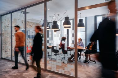 In the dynamic hustle and bustle of a business environment, a group of young business professionals walk down the corridor next to their office, while their colleagues collaborate inside, symbolizing clipart