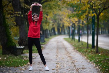 Atletik genç kadın, koşudan ve esnemeden sonra nefes alıyor ve dinleniyor. Sokakta Kadın Eğitimi ve Egzersizleri. Zayıf ve formda bir kız aktif fitness eğitiminden sonra esniyor.. 