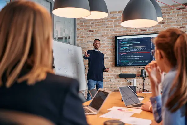 stock image In a corporate setting, an African-American businessman leads a meeting, passionately presenting a business plan to his attentive team, fostering collaboration and strategic thinking. 